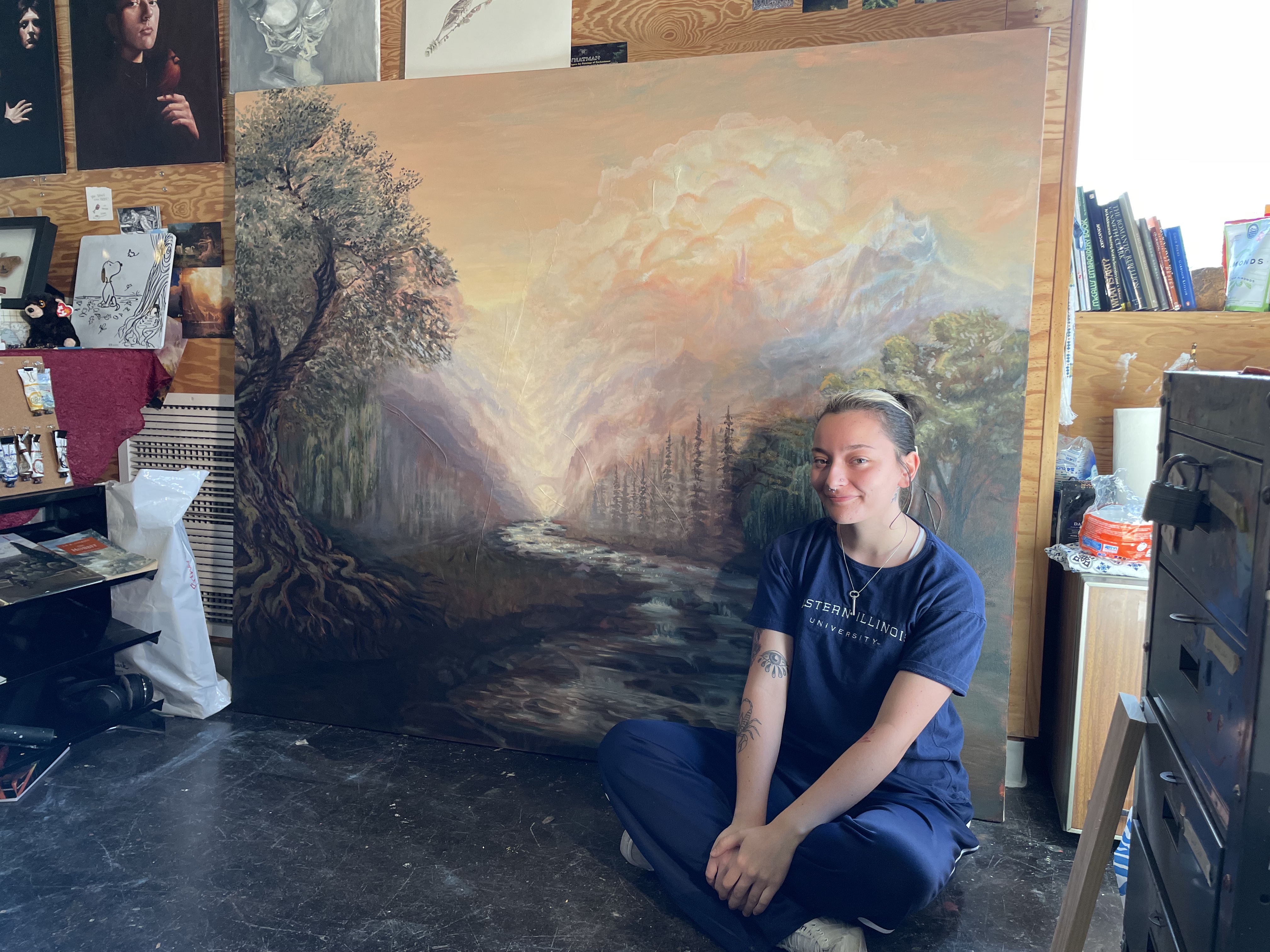 Isabella Gullotta sits with her 5 by 6 feet landscape painting, untitled