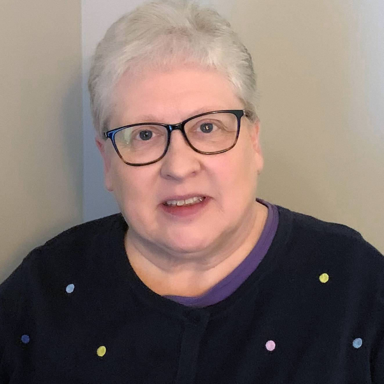 woman with short grey hair standing in corner