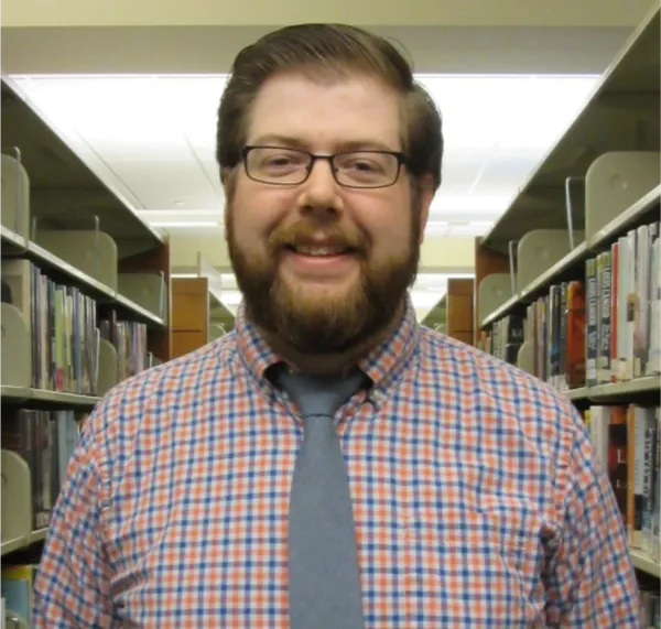 man with plaid shirt and glasses in library