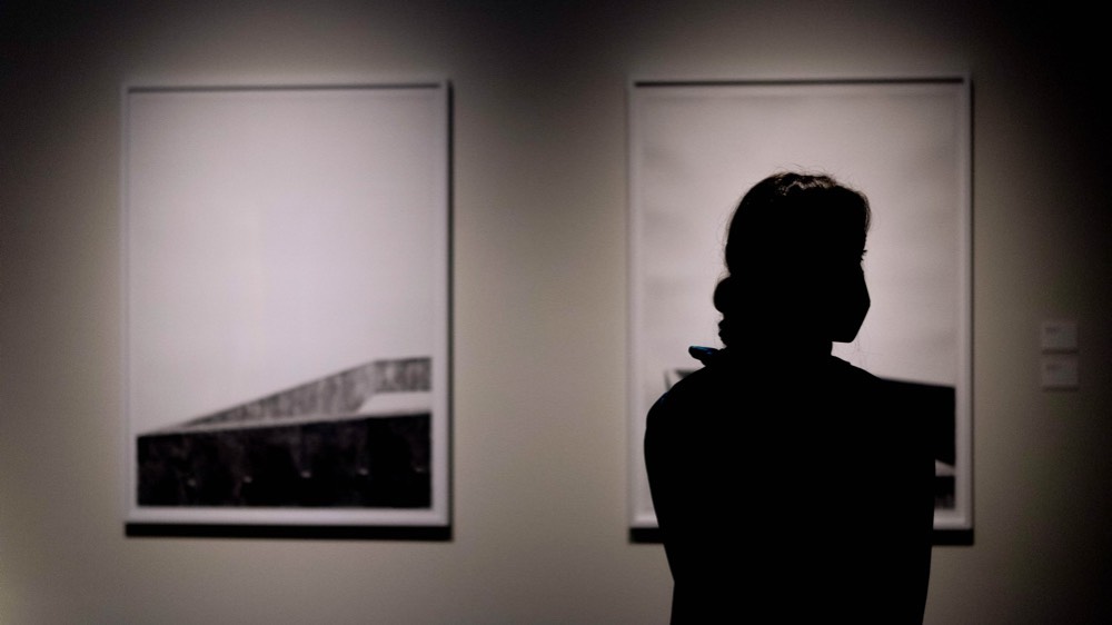  Silhouette of a woman looking at artwork in a Tarble gallery. 