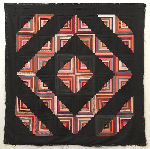 Amish quilt made up of log cabins blocks arranged in a square pattern, bright oranges on half of each block and black on the other